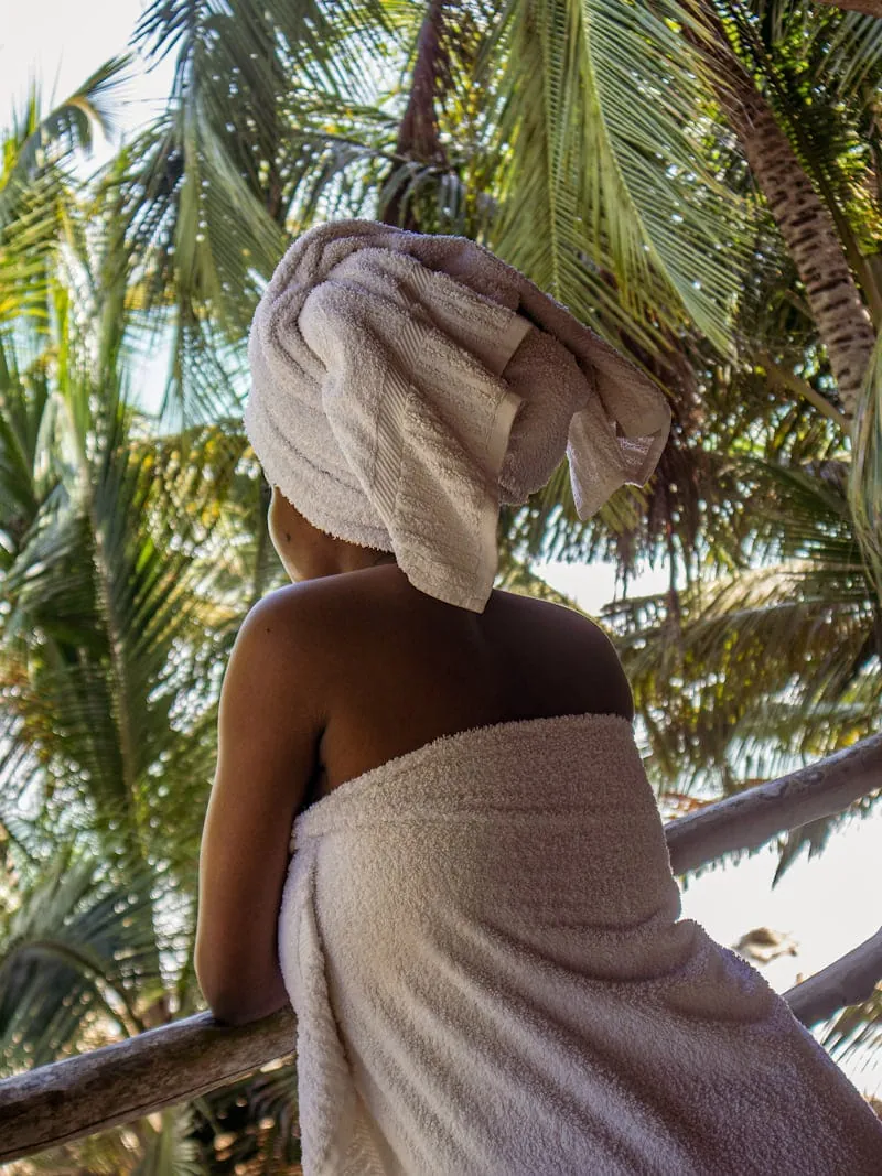 Spa guest wrapped in towels relaxing under palm trees after a massage in Diani Beach
